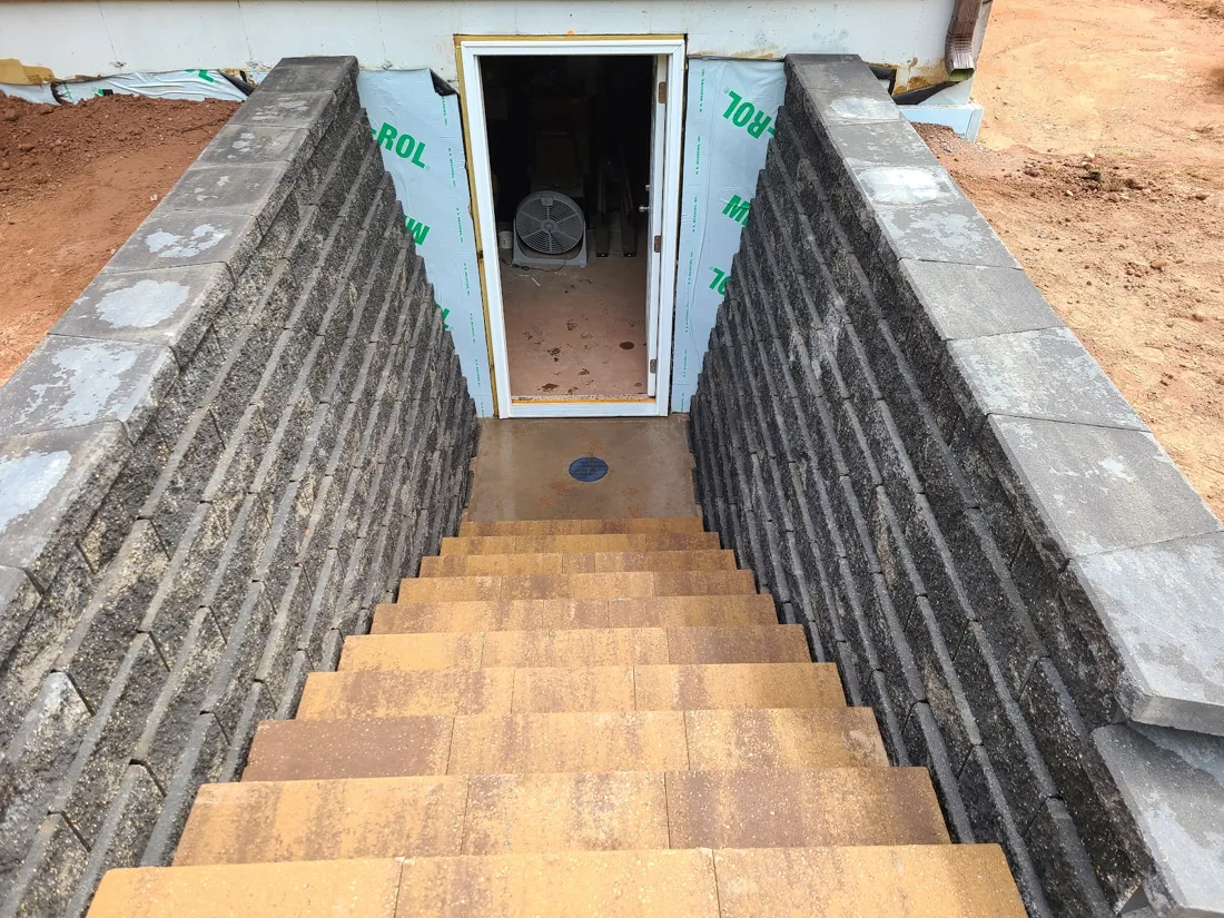 Close view down stone steps between block retaining walls leading to a doorway